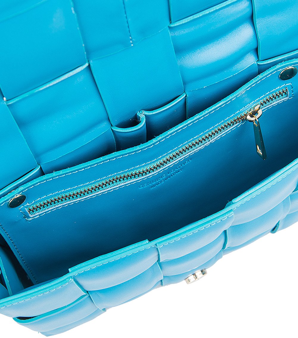 Interior view of blue leather tote bag with woven design, showing zip pocket and suede padding.
